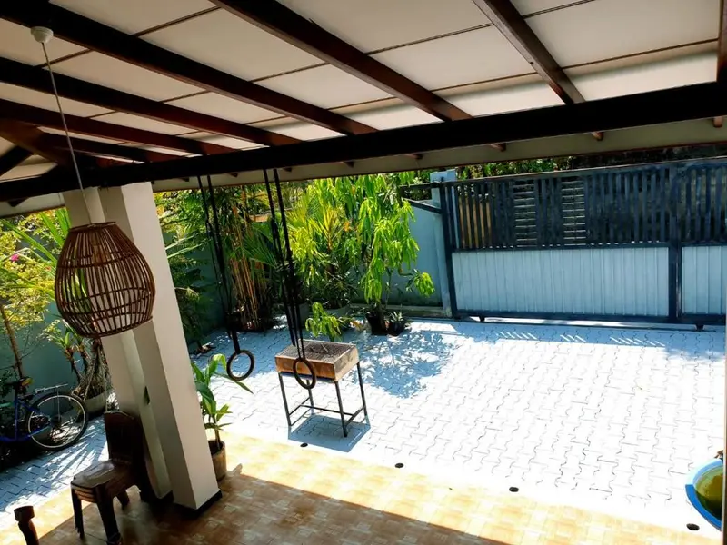 Covered patio with a rattan lamp, opening onto the garden