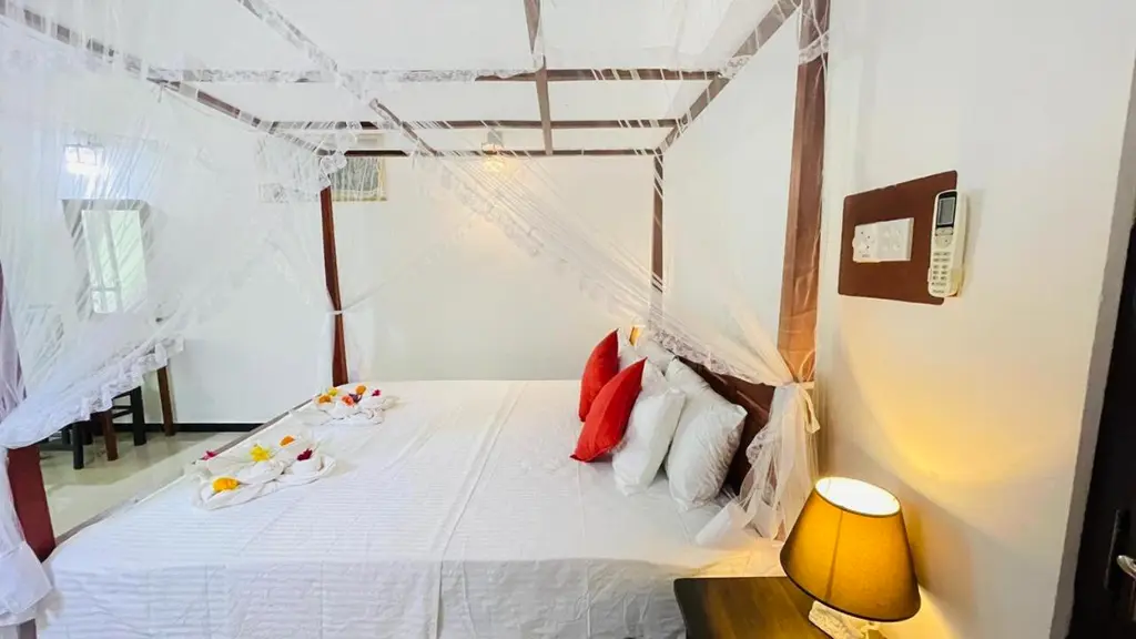 Double room with canopy bed, bedside lamps and red scatter cushions
