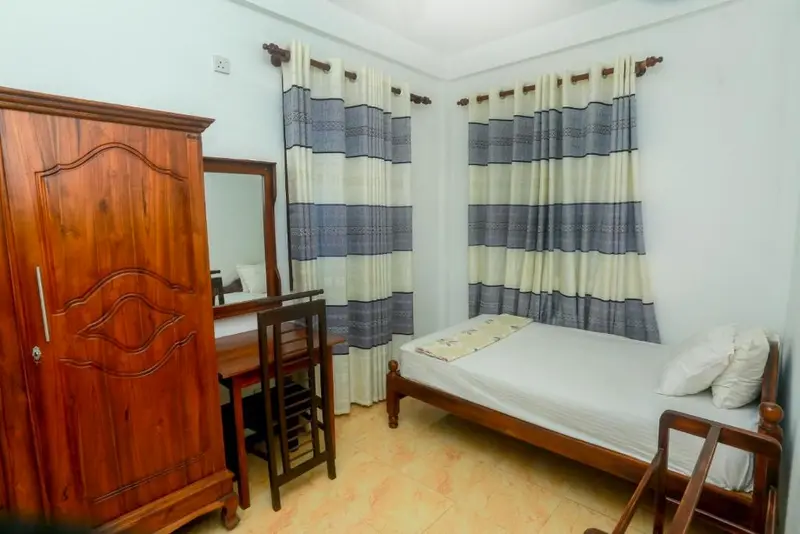 Guest room with carved wardrobe, dressing table and striped curtains
